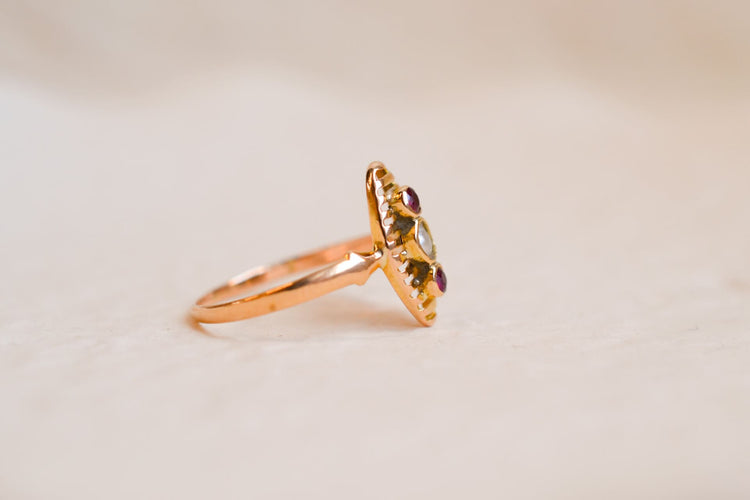 https://www.noircarat.fr/wp-content/uploads/2025/01/Bague-Navette-ancienne-en-Or-jaune-18-carats-sertie-d_une-Perle-et-de-pierres-rouges.jpg