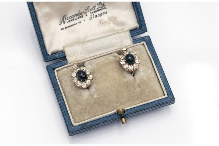 Kultaiset korvakorut, joissa on timantteja ja cabochon-hiottuja safiireja. 