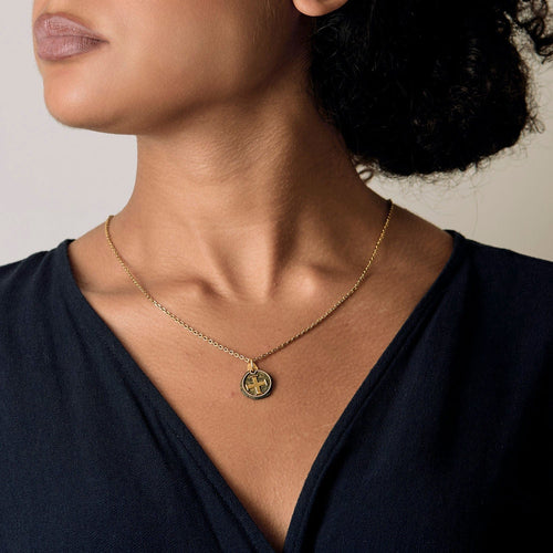 Old twisted yellow gold medal-cross on stone. 