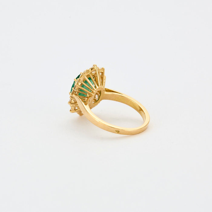 Yellow gold ring with central emerald surrounded by diamonds