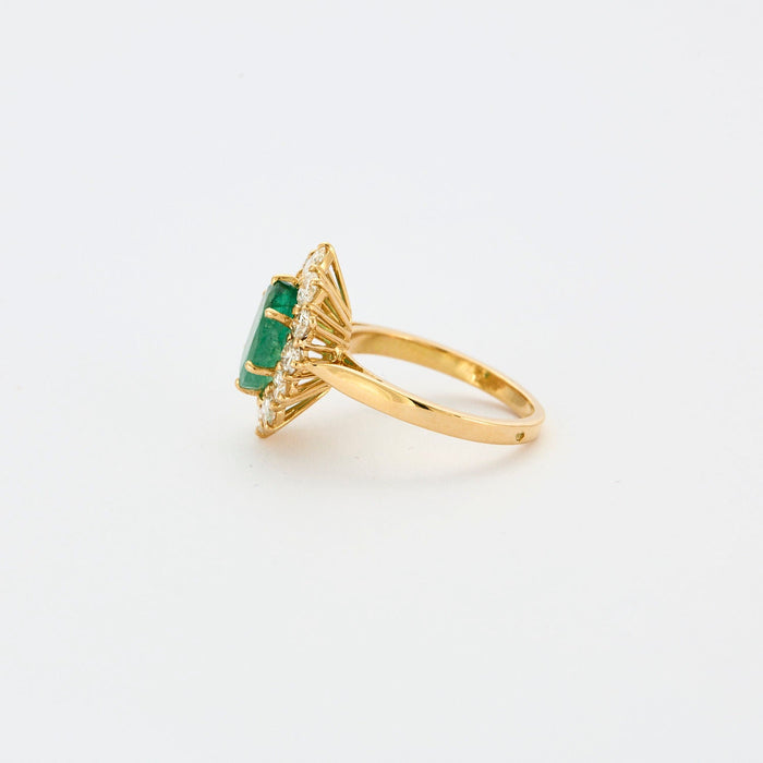 Yellow gold ring with central emerald surrounded by diamonds