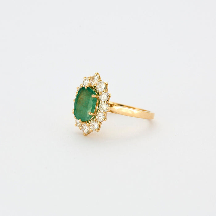 Yellow gold ring with central emerald surrounded by diamonds