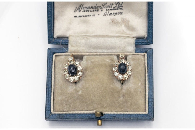 Kultaiset korvakorut, joissa on timantteja ja cabochon-hiottuja safiireja. 