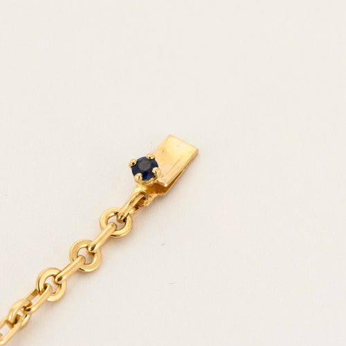 Kierretty keltakultainen rannekoru, jossa safiireja ja timantteja.