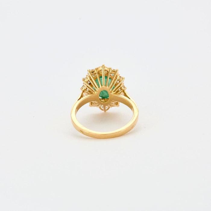 Yellow gold ring with central emerald surrounded by diamonds